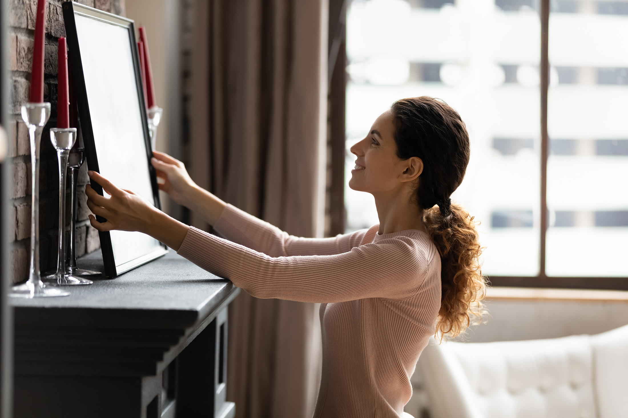 Woman adjusting a picture over her fireplace