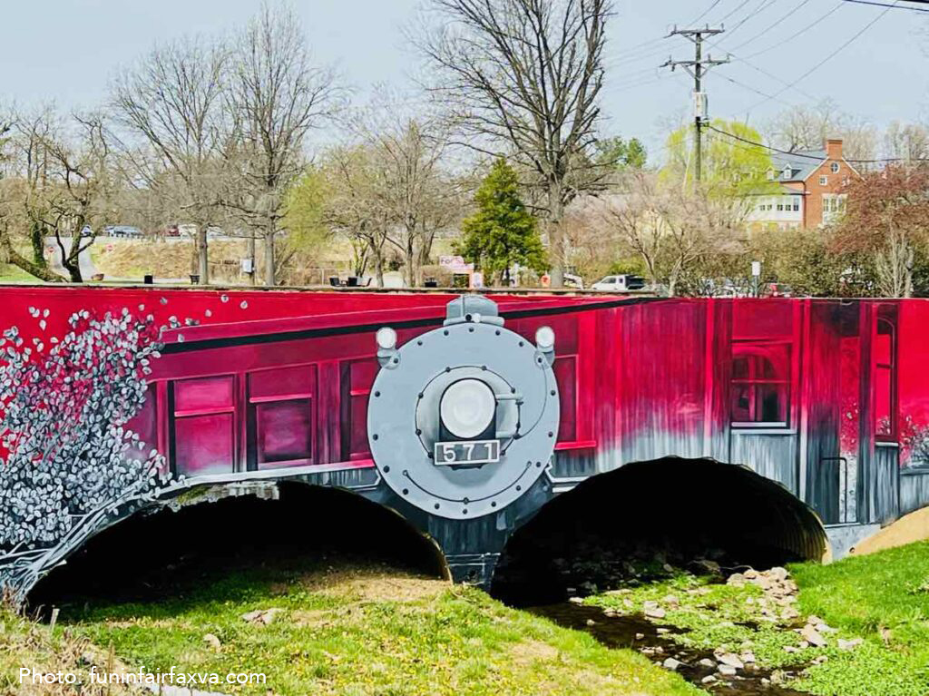 Mural of a train painted on a bridge